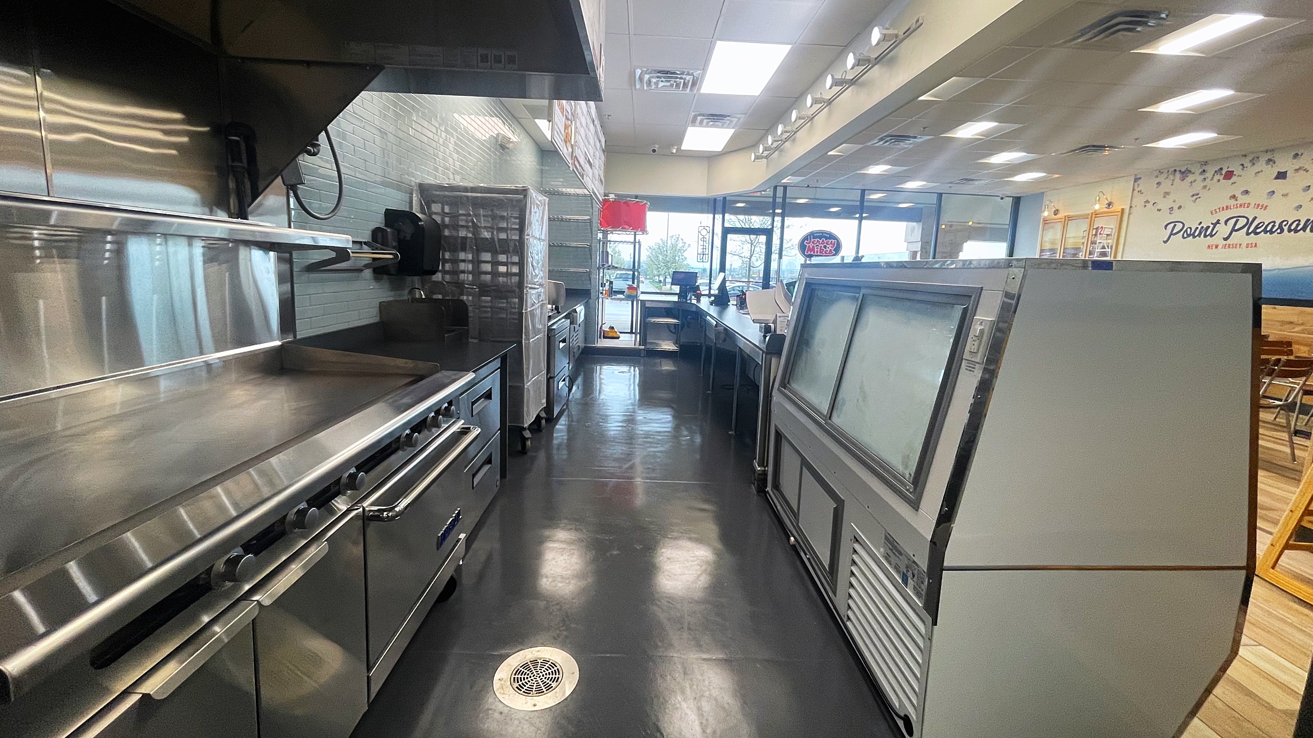 commercial fast food kitchen with counter, flat top grill, shelving, and more